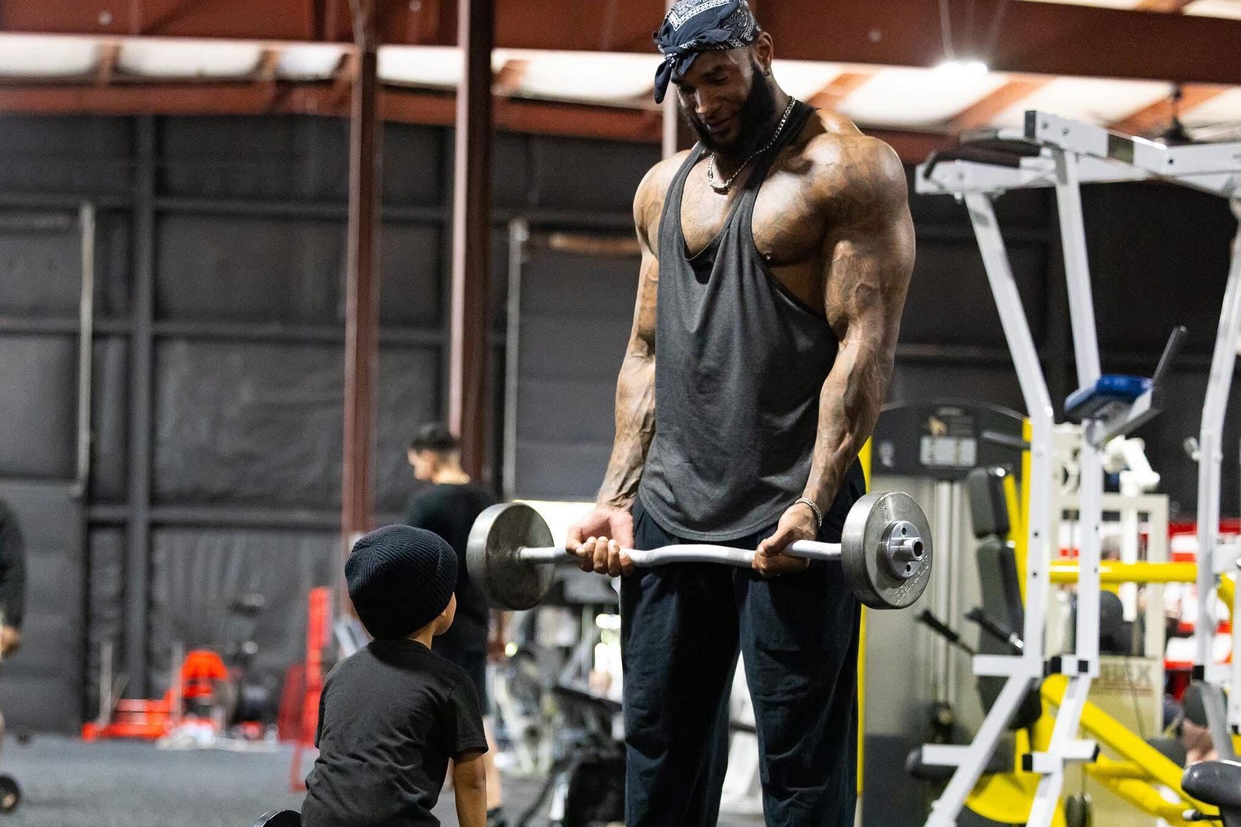 Coach Jae lifting in the gym beside his young son